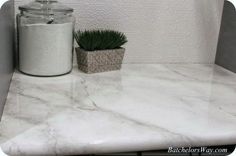 a white marble counter top with a potted plant on it and a canister