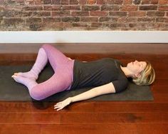 a woman is laying on a yoga mat in front of a brick wall with her eyes closed