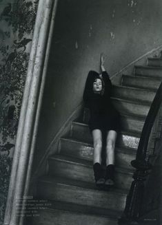 black and white photograph of woman sitting on stairs with her arms up in the air