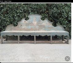 an old wooden bench sitting in front of a bush