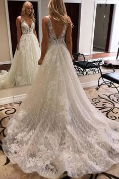 a woman in a wedding dress looking at herself in the mirror with her back to the camera