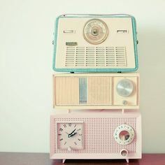 an old fashioned radio sitting on top of a wooden table next to a wall clock