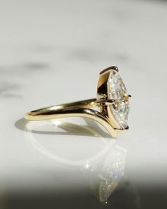 a yellow gold engagement ring with a single diamond set in the shants, on a white surface