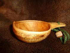 a wooden bowl with a green string around it and a wooden spoon in the shape of a flower