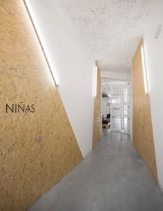 the hallway is lined with plywood paneling and white walls, along with an illuminated sign that reads nina's