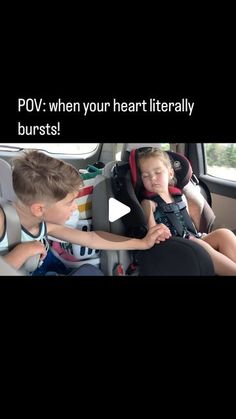 two children sitting in their carseats and one is holding the seatbelts