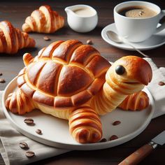 there is a turtle made out of bread on a plate with coffee and croissants