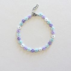 a beaded bracelet with blue, purple and white beads is displayed on a white surface