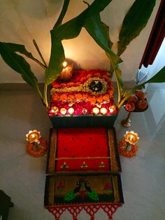 an arrangement of flowers, candles and other decorations on a table in a room with white walls