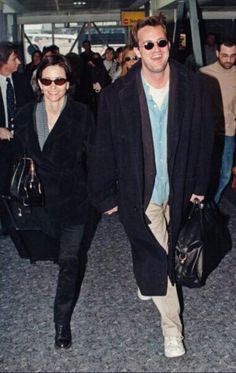 a man and woman walking through an airport