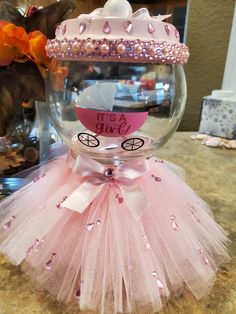 a pink tutu skirt and tiara on top of a glass vase with flowers in the background