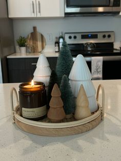 some candles are sitting on a tray in the middle of a kitchen counter with christmas trees