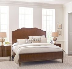 a bedroom with a bed, nightstands and two lamps on either side of the bed