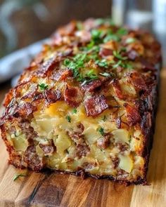 a piece of bread with bacon and cheese on it sitting on a wooden cutting board