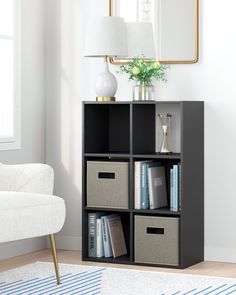 a living room with a white chair and a book shelf filled with books, binders and folders