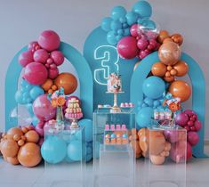 an assortment of balloons and cake on display in front of a blue arch with the number 3