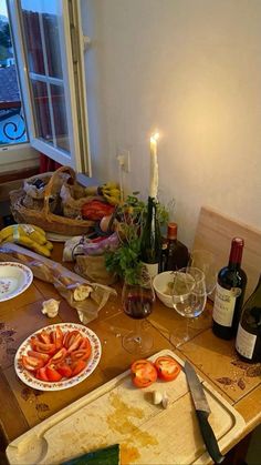 a table topped with plates and bottles of wine next to a window filled with food