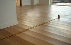 a measuring tape is on the floor in an empty room with wood floors and large windows