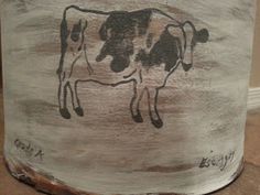 a cow painted on the side of a tree stump with words written in black ink