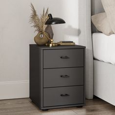 a night stand with three drawers and a lamp on top