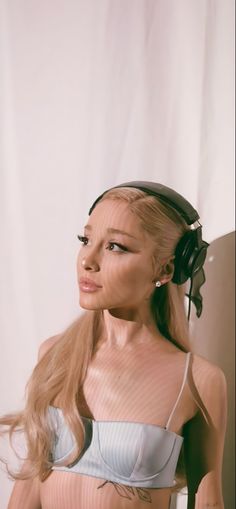 a woman with long hair wearing headphones on top of her head and looking off to the side