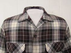 "Vintage 1960s button down shirt. Made of black, gray, brown and white plaid Rayon/wool. Has two chest flap pockets, button front, top button loop and button cuffs. Made by Acrallama. Size large. Actual measurements are: 48\" around the chest 48\" at the waist 18\" shoulder seam to shoulder seam 24.5\" shoulder seam to end of cuff 29\" overall length In very good condition." Brown Collared Flannel Shirt With Buttons, Classic Brown Flannel Shirt With Buttons, Retro Brown Shirt With Pockets, Vintage Collared Flannel Shirt With Buttons, Vintage Brown Flannel Shirt With Button Closure, Vintage Brown Flannel Shirt With Buttons, Brown Vintage Flannel Shirt With Button Closure, Vintage Brown Flannel Shirt, Brown Snap Button Button-up Flannel Shirt