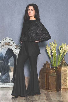 Black embroidered cape style top with side slits and embroidered drop hem.
Component: 1
Embroidered
Neckline: Round
Sleeve Length: Three Quarter
Fabric: Rayon flex
Color: Black
Embroidered cape style top
Drop beads embroidery
Note: The pants worn by the model are not for sale. - Aza Fashions Embroidered Cape, Beads Embroidery, Cape Style, Embroidered Neckline, Round Top, Drop Beads, Top For Women, Online Tops, Embroidered Top