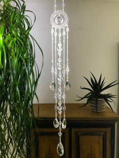 a white chandelier hanging from the side of a wooden cabinet next to a potted plant