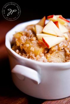 a white bowl filled with oatmeal topped with apple slices and sliced apples