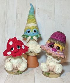 three crocheted little gnomes sitting on top of a pot with one wearing a hat