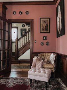 a chair sitting in the middle of a room next to a stair case with pictures on it