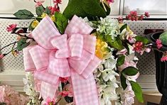 a pink and white flower arrangement with a large bow on it's front door