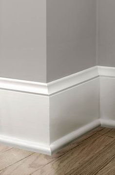 the corner of a room with white walls and wood flooring on top of it