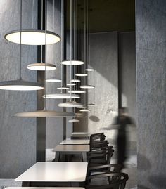 several tables and chairs are lined up against the wall with lights hanging from them in an empty room