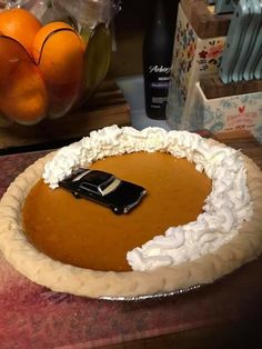 a pumpkin pie with whipped cream and a black car on top, ready to be eaten