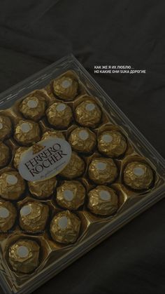 a box of gold foiled chocolates on a black tablecloth with a white tag