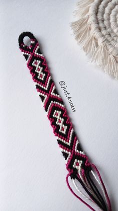 a pink and black beaded bracelet with tassels on white paper next to a hat