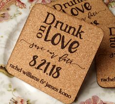 two cork coasters sitting on top of a floral table cloth with the words drunk and love printed on them