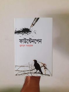 a hand holding up a book with a bird on it's cover and the title written in two languages