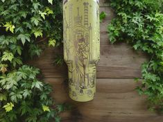 a yellow water bottle sitting on top of a wooden table next to green plants and leaves