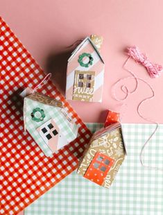 three small houses made out of paper sitting on top of a table next to each other