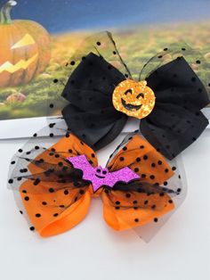 two halloween hair clips with black and orange polka dots, one has a pumpkin on it