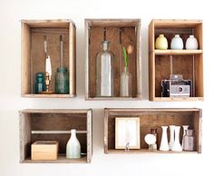 three wooden boxes with different items in them on the wall, one has a camera and two are empty