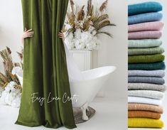 a woman standing next to a bath tub in front of a stack of towels and flowers