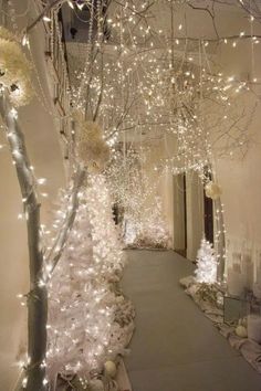 an indoor walkway is decorated with white lights and christmas decorations on the trees in the hallway