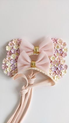 a pink headband with flowers on it and a bow tie attached to the side