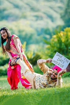 a man and woman laying in the grass with a sign