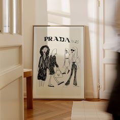 a framed fashion poster on the wall next to a stair case in a room with wooden floors