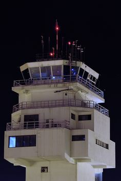 an airport control tower at night with lights on it's top and stairs leading up to the second floor