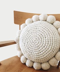 a white crocheted pillow sitting on top of a wooden chair next to a table